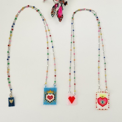 Colares de miçangas com pendentes decorados e broche em forma de libélula sobre fundo branco