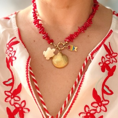 Colar artesanal colorido com pendentes de tartaruga, concha e peixe, usado com blusa bordada em vermelho.
