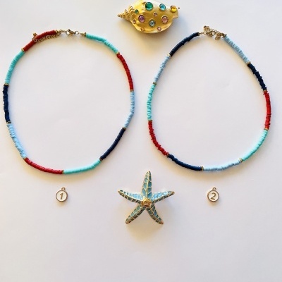 Dois colares coloridos com etiquetas numeradas, concha dourada com pedras e estrela-do-mar azul