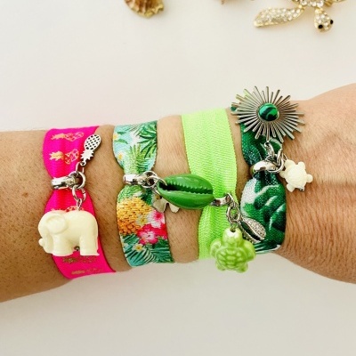 Pulseiras elásticas coloridas com pingentes usadas no pulso sobre fundo branco