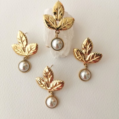 Brincos dourados com folhas e pérolas pendentes em fundo branco