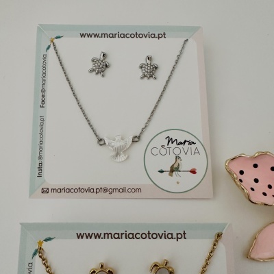 Conjunto de bijuteria com colares e brincos de tartarugas e pomba em metal prateado e dourado.