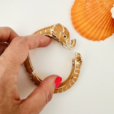 Bracelete dourado em forma de elefante com pedras brilhantes e concha laranja