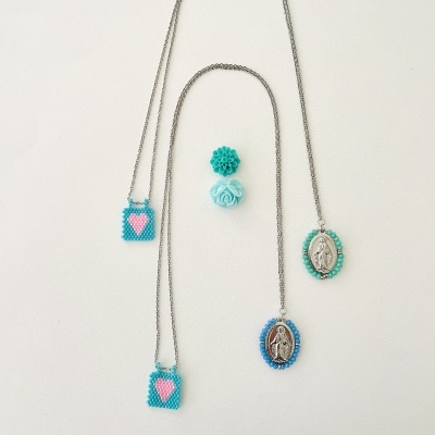 Colares com pendentes azuis e rosas e anéis azuis, sobre fundo branco