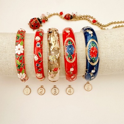 Pulseiras rígidas coloridas com padrões florais e etiquetas numéricas, sobre suporte tecido