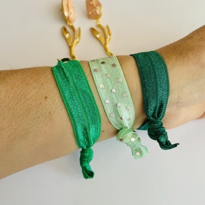 Braçadeiras elásticas verdes com padrão de bolinhas prateadas e brincos dourados com folhas corais