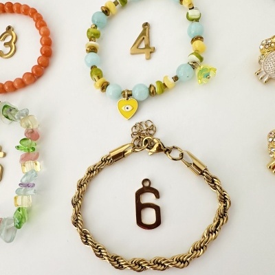 Pulseiras coloridas e douradas com números pendentes sobre fundo branco