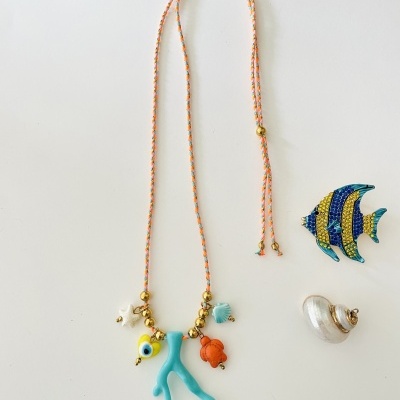 Colar temático do mar com pendentes coloridos e broches de peixe e concha sobre fundo branco