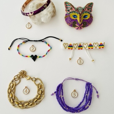 Bijuteria colorida e numerada sobre fundo branco, incluindo pulseiras e broche.