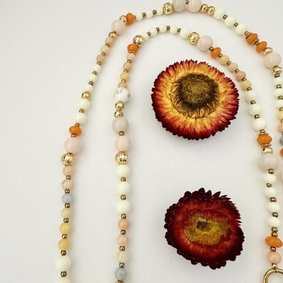 Colar de contas coloridas e flores secas sobre fundo branco.