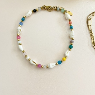 Colar colorido com pérolas brancas e contas douradas em fundo claro
