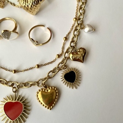 Bijuterias douradas com pendentes em forma de coração sobre fundo branco