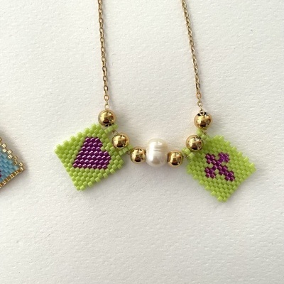 Colar com pendentes de contas verdes e pérola central sobre fundo branco