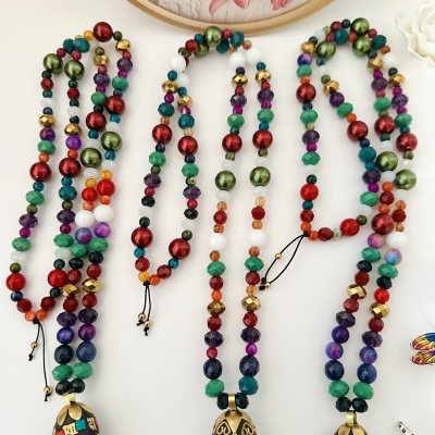 Três colares multicoloridos com contas facetadas e pendentes de metal gravados
