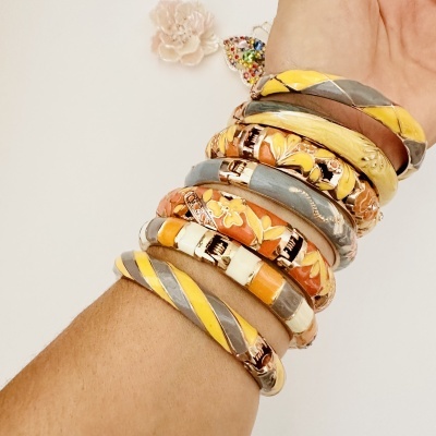 Pulseiras coloridas com padrões florais e lisos em pulso com fundo branco.