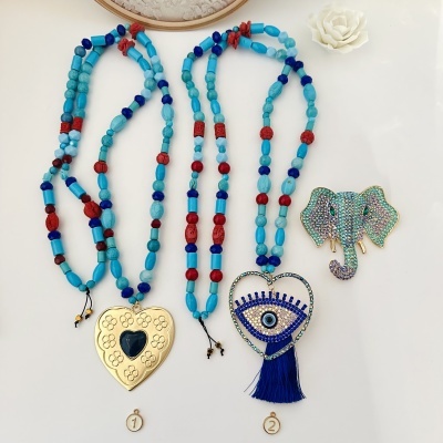 Dois colares coloridos com pendentes de coração e um broche de elefante com pedras brilhantes