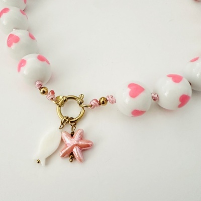 Colar branco com corações cor-de-rosa e pendentes em forma de peixe e estrela do mar.