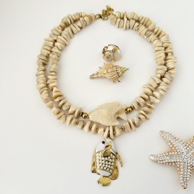 Colar de contas bege claro com pendente de peixe dourado e pérola, broche estrela do mar com pérolas e brilhantes e dois pendentes de conchas.
