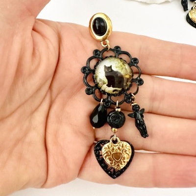 Brinco pendente com elementos dourados e pretos e imagem de gato