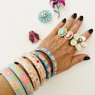 Mão com anéis, pulseiras florais e broches coloridos