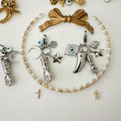 Pendentes prateados com símbolos variados em suporte branco com laço castanho e números