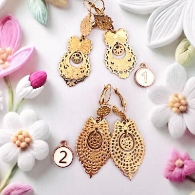 Dois pares de brincos dourados com etiquetas 1 e 2 em fundo decorado com flores de tecido