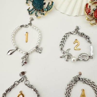 Quatro pulseiras com números dourados 1, 2, 3, 4 e dois broches de caranguejo decorativos.