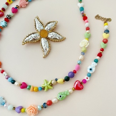 Colares coloridos com miçangas e broche de flor over fundo branco