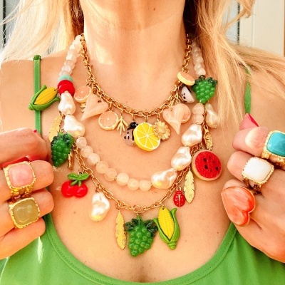 Colar com pingentes de frutas e anéis coloridos em pessoa com roupa verde