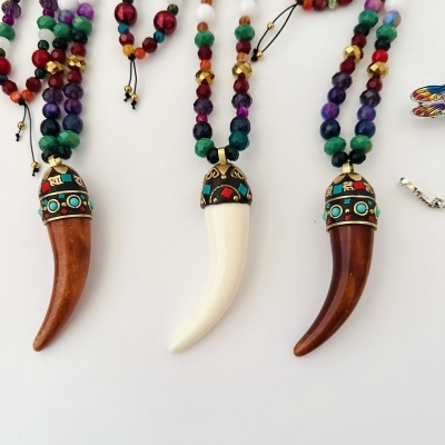 Colares coloridos com pendentes em forma de presa em fundo branco