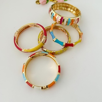 Braceletes metálicos coloridos com detalhes esmaltados sobre fundo branco