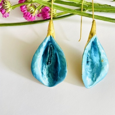 Brincos em forma de folhas azul metálico e dourado junto a flores rosas