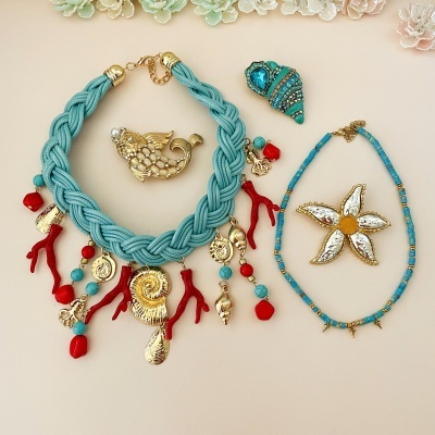 Colares e broches temáticos marinhos coloridos sobre fundo claro.