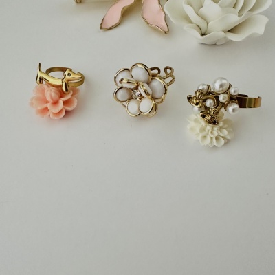 Anéis dourados decorativos sobre flores em fundo branco