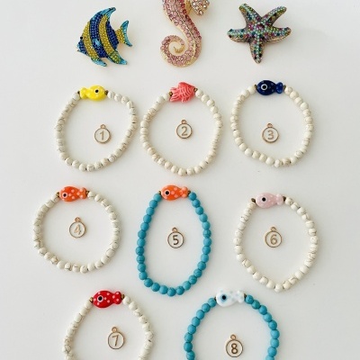 Pins de animais marinhos coloridos e pulseiras com contas e figuras de peixes numeradas