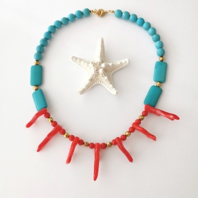 Colar azul-turquesa com pendentes vermelhos ao redor de estrela-do-mar branca