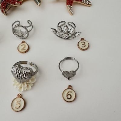 Cinco anéis metálicos prateados com diferentes designs sobre fundo branco