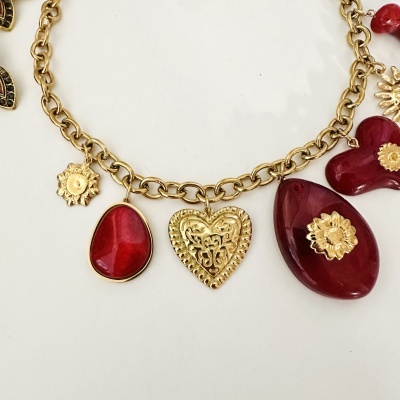 Colar dourado com pendentes vermelhos e dourados em várias formas sobre fundo branco