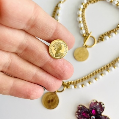 Colar de pérolas com botão dourado e broche em forma de trevo com pedras roxas