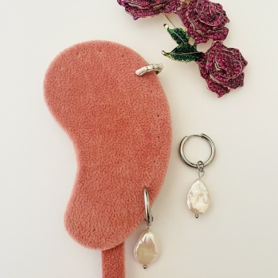 Brincos e anel de prata com pérolas e broche de rosas vermelhas brilhantes sobre suporte cor de rosa