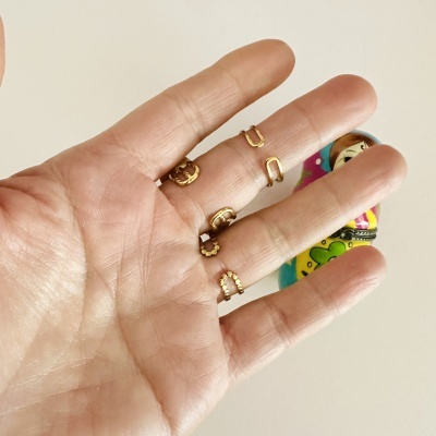 Cinco anéis dourados em uma mão humana com figura colorida desfocada no fundo