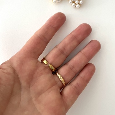 Mão com anéis dourados e brincos de pérolas