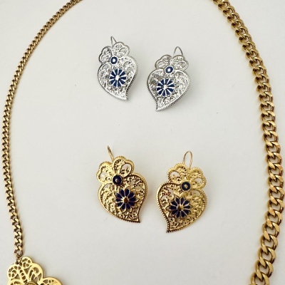 Três pares de brincos em formato de coração e flor, em prateado e dourado com detalhes azuis