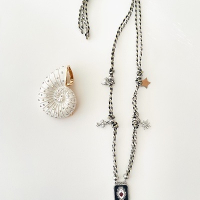 Anel em concha branca e colar com pingentes variados em fundo branco.
