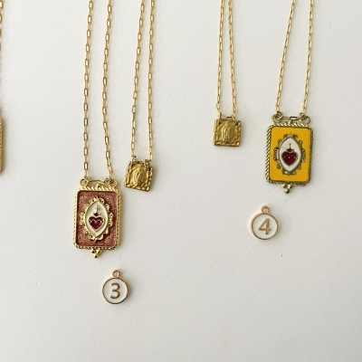 Colares dourados com pendentes decorativos retangulares e etiquetas numeradas 3 e 4