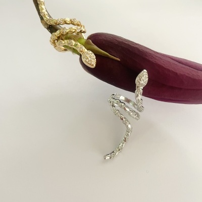 Dois anéis de serpente, em dourado e prateado, sobre caule e flor roxa