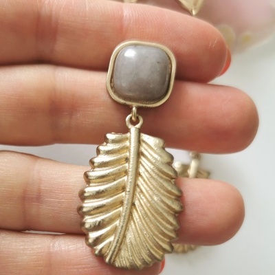 Brincos dourados com base cinza e pendente em forma de folha