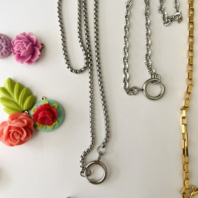 Colares metálicos com pingentes coloridos em superfície branca