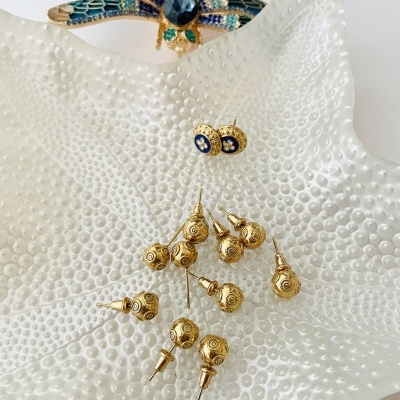 brincos dourados em prato branco com textura de bolhas