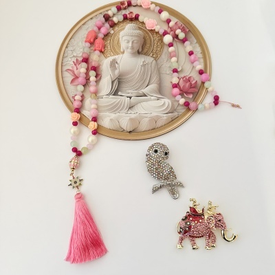 Colar colorido com franja rosa e duas broches brilhantes, uma coruja e um elefante